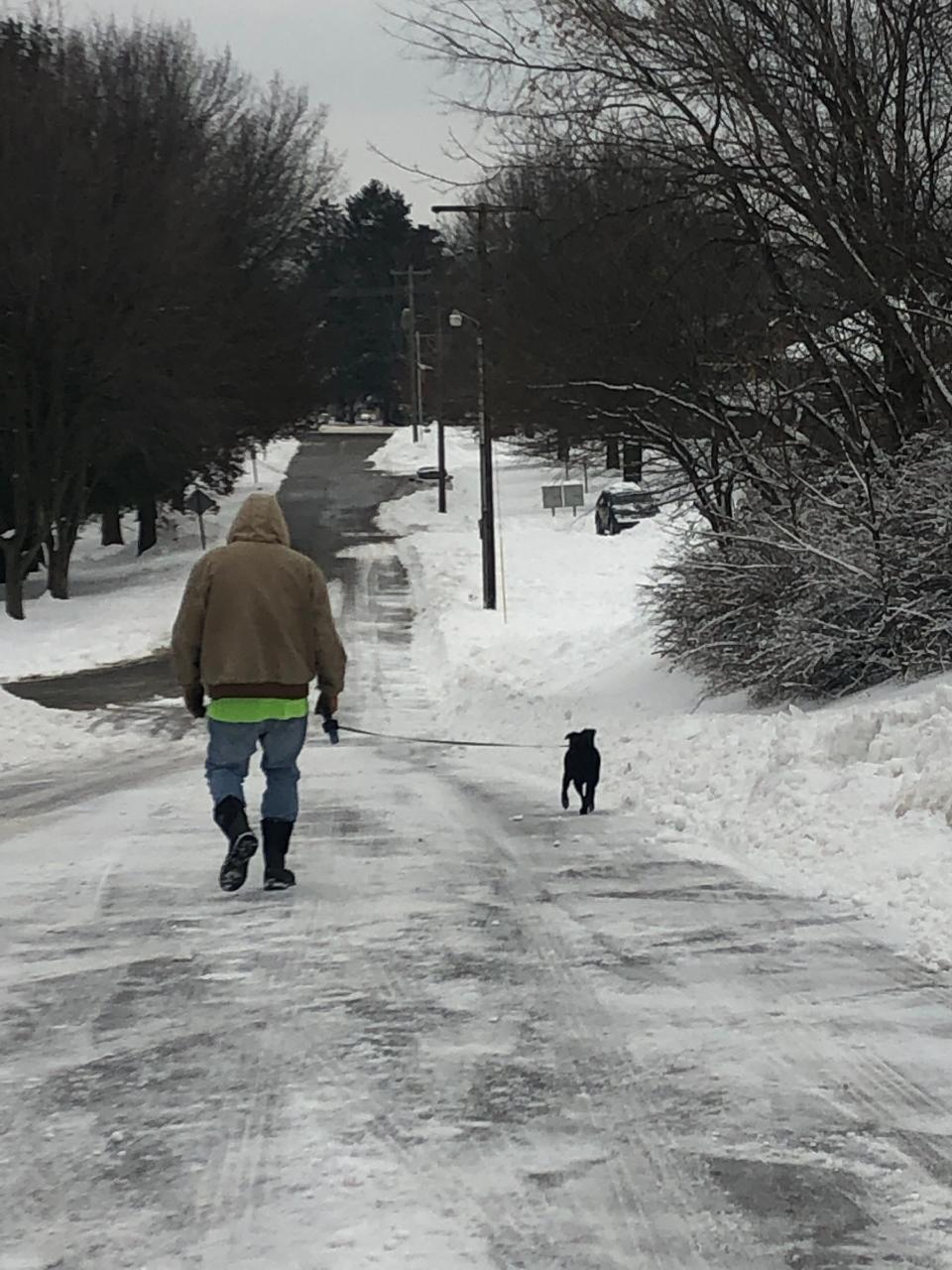 Dave Oberlin of Plain Township enjoys a snowy walk Monday with his dog Lucy. The Canton region got hit with about a foot of snow late Sunday into Monday morning.