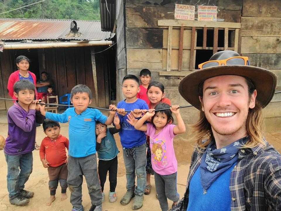 Daniel James of Canton, who recently completed a solo bicycling trip through Central America, poses with local children during his travels.