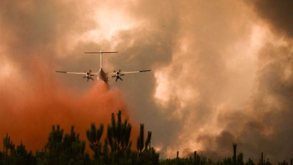 Bomberos combatiendo con una avión un incendio