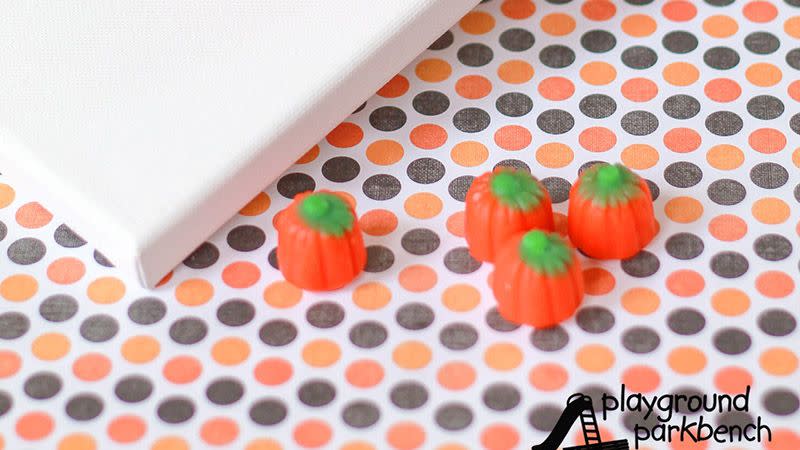 halloween pumpkin toss activity for preschool kids with black mini cauldrons for receptacles and candy pumpkins for tossing