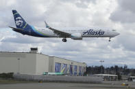 An Alaska Airlines Boeing 737-9 Max flies over Boeing's manufacturing facility in Everett, Wash., Monday, March 23, 2020, north of Seattle. All 737 Max planes remain grounded after two deadly crashes, but test and positioning flights continue to be made. Boeing announced Monday that it will be suspending operations and production at its Seattle area facilities due to the spread of the new coronavirus. (AP Photo/Ted S. Warren)