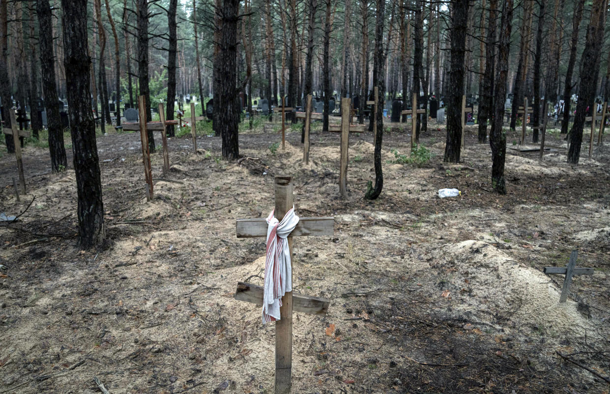 A view shows unidentified graves of civilians and Ukrainian soldiers in a cemetery, in the recently retaken area of Izium, Ukraine, Friday, Sept. 16, 2022. Ukrainian authorities discovered a mass burial site near the recaptured city of Izium that contained hundreds of graves. It was not clear who was buried in many of the plots or how all of them died, though witnesses and a Ukrainian investigator said some were shot and others were killed by artillery fire, mines or airstrikes. (AP Photo/Evgeniy Maloletka)