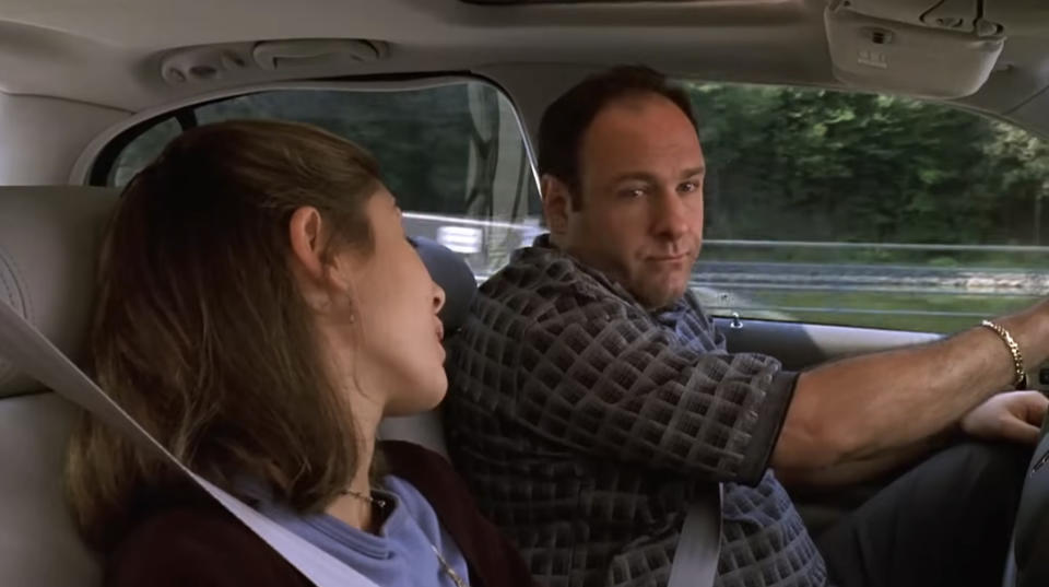 Jamie-Lynn Sigler and James Gandolfini in a car scene from "The Sopranos," with Gandolfini wearing a patterned shirt and Sigler looking towards him