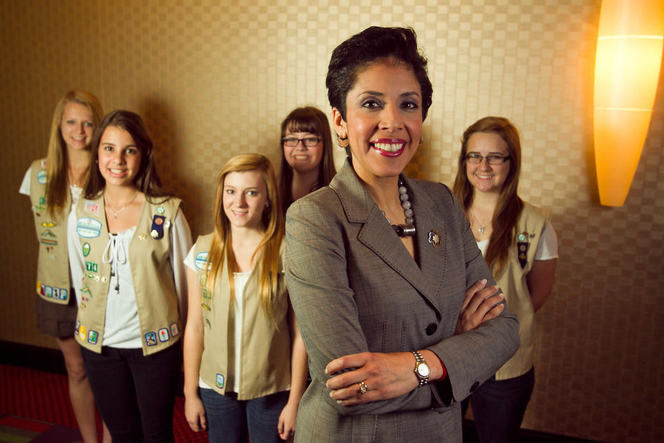 FILE - In this March 28, 2012 file photo, Girl Scouts of the USA CEO Anna Maria Chavez, foreground, stands with members of Girl Scout Troop 1774. Compounding the problems at the organization are tensions at GSUSA headquarters in New York, where several senior executives have quit or been ousted since Chavez took over as CEO in 2011. In June 2013, some of the roughly 325 employees there were invited to take early retirement, and Chavez said an unspecified number of layoffs were expected in August 2013 to offset the revenue losses. Chavez insists the GSUSA is on the right track, although she acknowledged in an interview that sweeping changes in structure and programs over the past 10 years have been difficult for many in the Scouts' extended family. From left are Megan Zimmerman, 17, Molly Gulden, 15, Jessica Krehbiel, 16, Shelby Johnstone, 15, and Lauren McCabe, 16, all of Shadow Mountain High School in Phoenix. (AP Photo/The Arizona Republic, Michael Schennum)