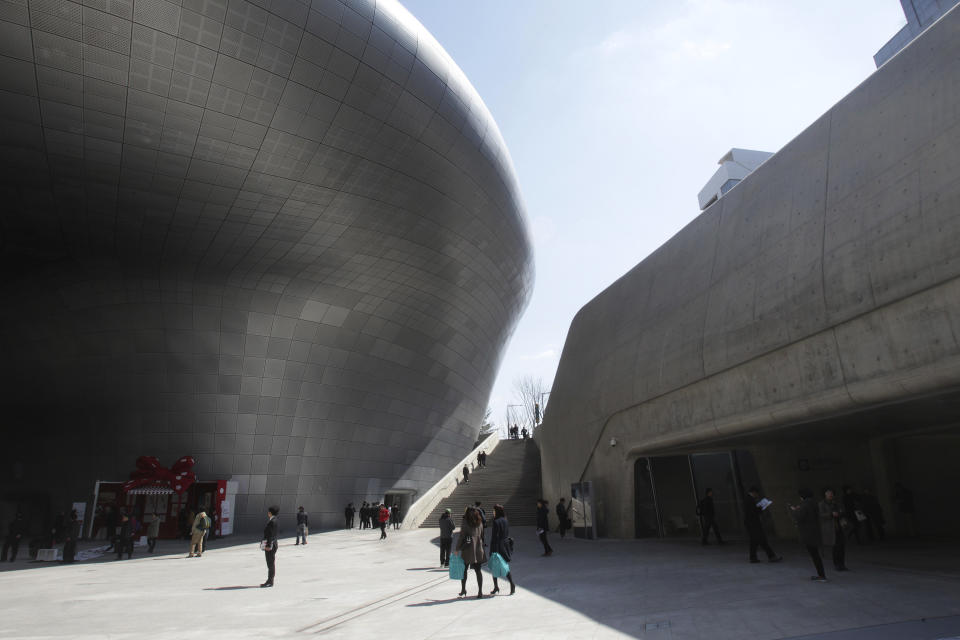 Visitors are dwarfed by Dongdaemun Design Plaza in Seoul, South Korea, Friday, March 21, 2014. The $450 million building funded by Seoul citizen's tax money finally opened to public on Friday after years of debates about transforming a historic area with an ultra-modern architecture. (AP Photo/Ahn Young-joon)