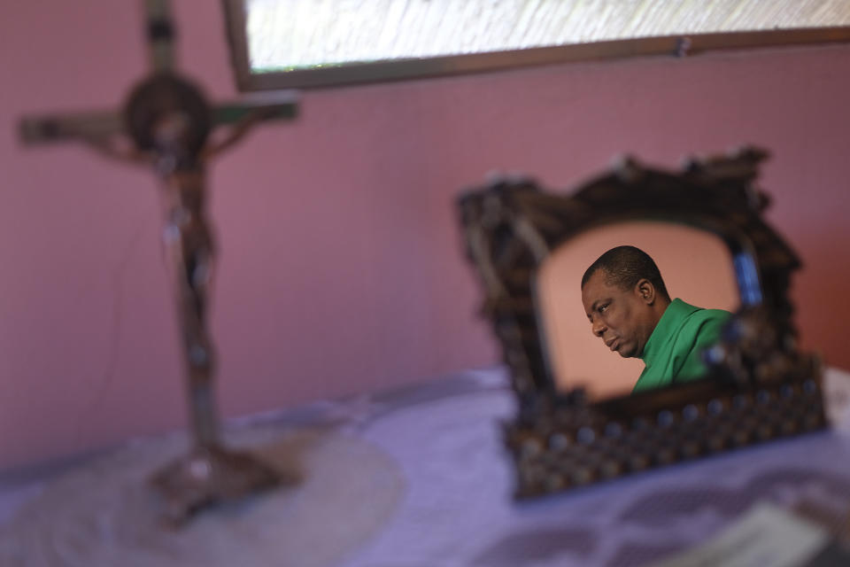 FILE - Reflected in a mirror, Catholic priest Jean-Nicaisse Milien changes clothes to start giving a Mass in Port-au-Prince, Haiti, Sunday, Nov. 7, 2021. Father Milien was kidnapped for 20 days along with other priests, nuns, and civilians in April by the 400 Mawozo gang who have been holding 17 members of a U.S.-based missionary group Christian Aid Ministries for more than 3 weeks. (AP Photo/Matias Delacroix, File)