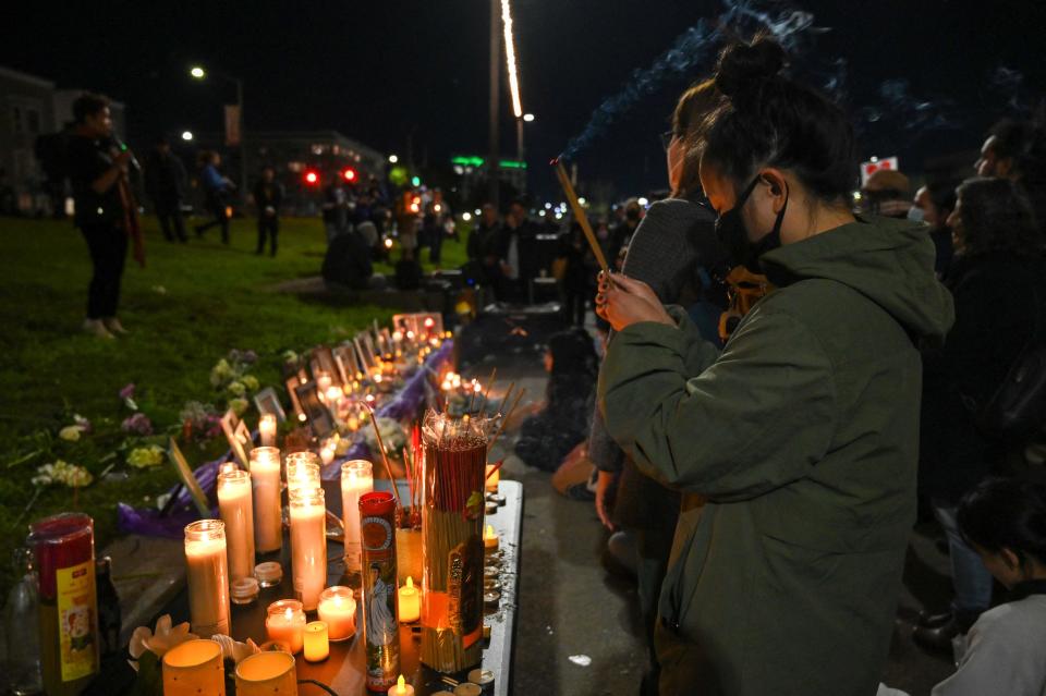 Jamie Lam prays during a candlelight vigil for the recent shootings at Monterey Park, Half Moon Bay and East Oakland in Oakland, California on January 25, 2023.