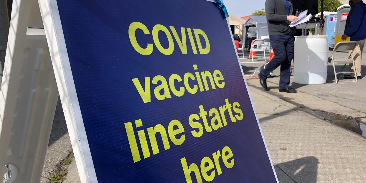 A sign reading "COVID vaccine line starts here" in San Franisco.