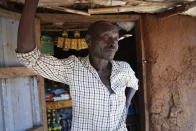 Farmer Jacob Wani, 45, who fled civil war and returned home after 8 years only to find himself banned from accessing his agricultural land due to it being contaminated with landmines, stands next to his small shop in Moli village, Eastern Equatoria state, in South Sudan Friday, May 12, 2023. As South Sudanese trickle back into the country after a peace deal was signed in 2018 to end a five-year civil war, many are returning to areas riddled with mines left from decades of conflict. (AP Photo/Sam Mednick)