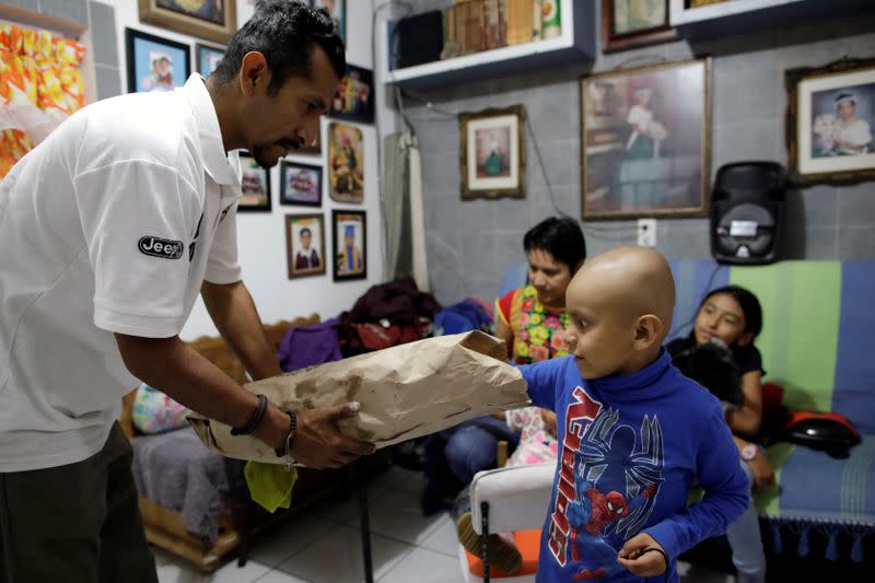 Hermes Soto takes a cookie as his father, Armando Soto, holds a bag in his house in Mexico City