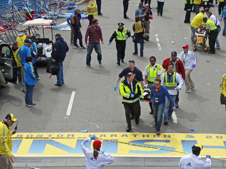FILE— In this Monday April 15, 2013 file photograph, emergency workers aid injured people at the finish line of the 2013 Boston Marathon following two explosions in Boston. Boston is marking eight years since the bombing at the 2013 Boston Marathon killed three people and injured scores of others. Acting Mayor Kim Janey on Thursday, April 15, 2021, paid a noontime visit to the downtown memorial marking the bombing site. (AP Photo/Charles Krupa, File)