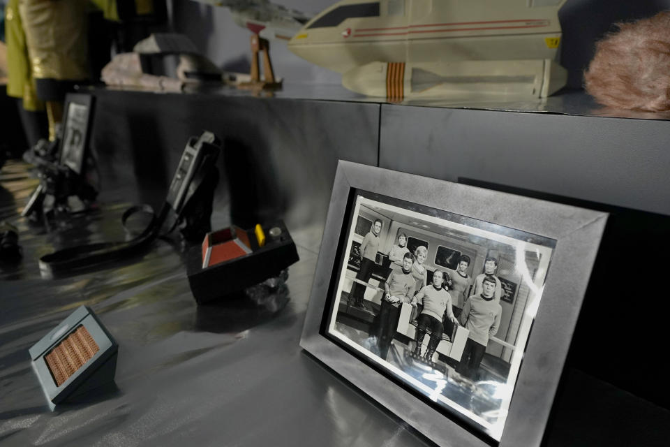 A photograph of the actors from the 1960's television series, Star Trek, sits on display amongst props from the show at Heritage Auctions, Thursday, Aug. 30, 2023, in Irving, Texas. While Greg Jein's work over nearly half a century making miniature models in Hollywood included such iconic creations as the alien mothership in "Close Encounters of the Third Kind," he was also a lifelong collector of costumes, props, scripts, artwork and photographs from the shows he loved, including countless rare items from the "Star Trek" and "Star Wars" franchises. Thousands of those items, including those Jein collected and those he created, will be offered up by Heritage Auctions next month in Dallas. (AP Photo/Tony Gutierrez)