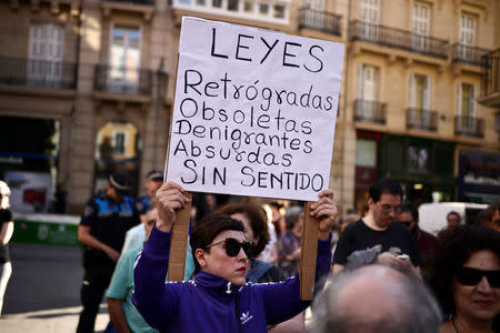 A woman carries a placard reads "Obsolete, Retrograde, Insulting and Absurd Laws" before a protest against the provisional release granted to five men cleared of the gang rape of a teenager and convicted of a lesser crime of sexual abuse in Pamplona, Spain, June 22, 2018. REUTERS/Vincent West