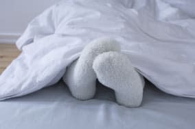 detail of woman lying in bed showing feet in woollen socks.Keywords:   People, Heat, Cold Temperature, Bed, Horizontal, Indoor