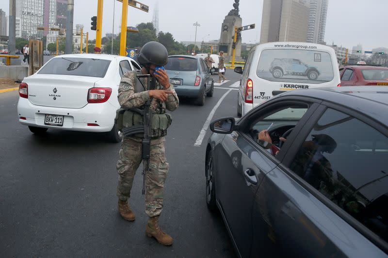 A soldier checks drivers' documents after Peru's government deployed military personnel to block major roads, as the country rolled out a 15-day state of emergency to slow the spread of coronavirus disease (COVID-19), in Lima