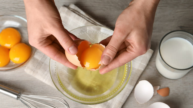 Hands cracking an egg into bowl