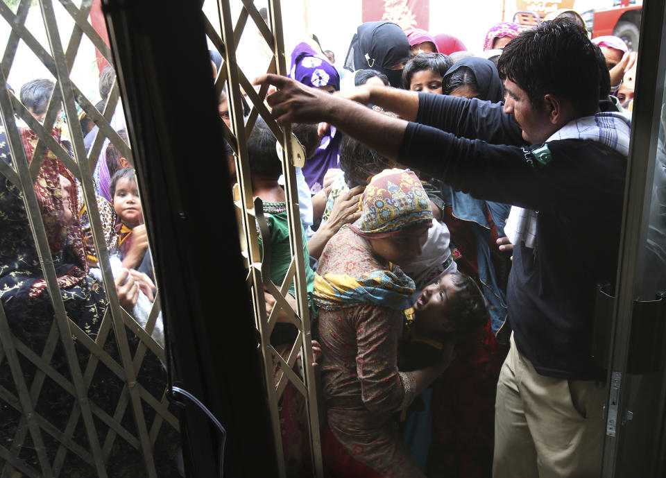 Pakistani villagers push to enter a hospital for blood screening for HIV in a village near Ratodero, a small town in southern province of Sindh in Pakistan where the outbreak of deadly disease took place last month, Thursday, May 16, 2019. Officials say about 500 people, mostly children, have tested positive for HIV, the virus that causes AIDS, in a southern Pakistani provincial district. A local doctor who has AIDS has since been arrested and is being investigated for possibly intentionally infecting patients.. (AP Photo/Fareed Khan)