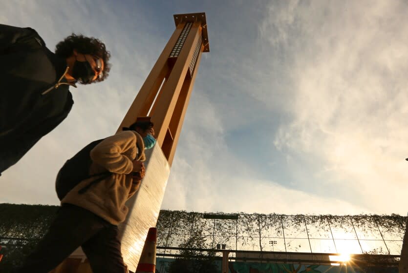 LOS ANGELES, CA - JANUARY 14, 2022 - - Pedestrians walk past one of the columns that will make up the gateway arch in Historic Filipinotown on January 14, 2022. Eliseo Art Silva is the designer of the Historic Filipinotown gateway currently being erected and will hang over Beverly Blvd. The arch is intended to act as a cultural marker to welcome people into the neighborhood. But the arch is also a symbol for people to project onto it their ideals and values of what it means to be Filipino American. Longtime community members see their own family histories reflected in the project. Others see it as a part of Filipino Americans' struggle for visibility in White America. (Genaro Molina / Los Angeles Times)