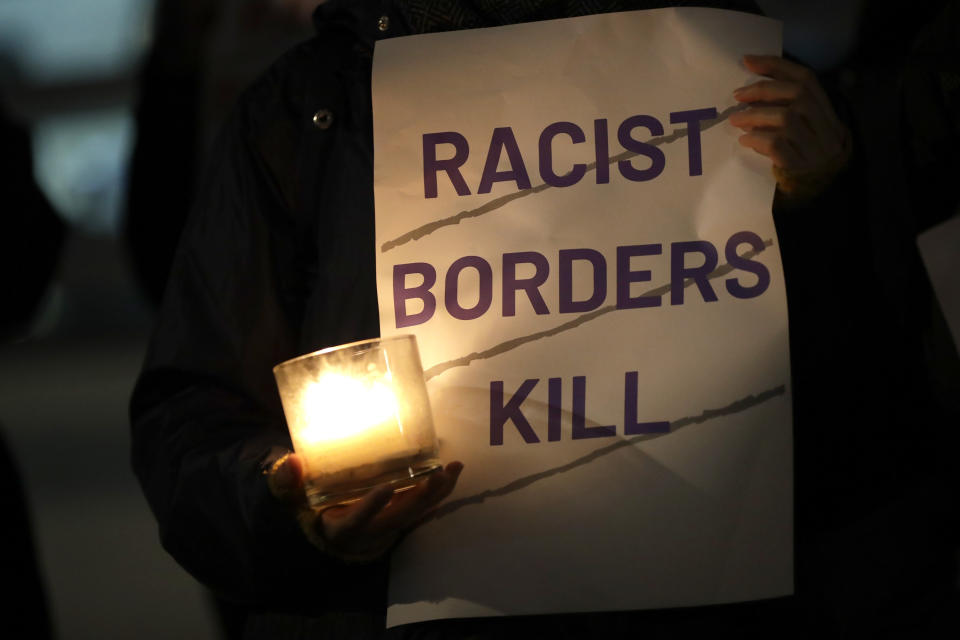 A demonstrator holds a candle and a banner during a vigil for the 39 lorry victims, outside the Home Office in London, Thursday, Oct. 24, 2019. Authorities found 39 people dead in a truck in an industrial park in southeast England on Wednesday and arrested the driver on suspicion of murder in one of Britain's worst human-smuggling tragedies. (AP Photo/Kirsty Wigglesworth)