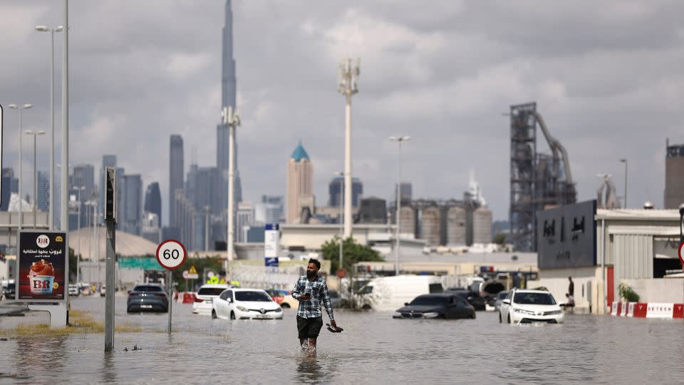 A man walks in flood water caused by heavy rains, with the Burj Khalifa tower visible in the background, in Dubai, United Arab Emirates, April 17, 2024. REUTERS/Amr Alfiky - Amr Alfiky/Reuters