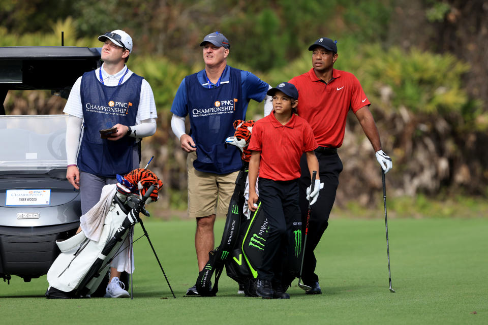 ORLANDO, FLORIDA - DECEMBER 19: Charlie Woods and Tiger Woods wait to play a shot on the first hole with caddies Joe LaCava and Joe LaCava Jr. during the final round of the PNC Championship at the Ritz Carlton Golf Club Grande Lakes   on December 19, 2021 in Orlando, Florida. (Photo by Sam Greenwood/Getty Images)