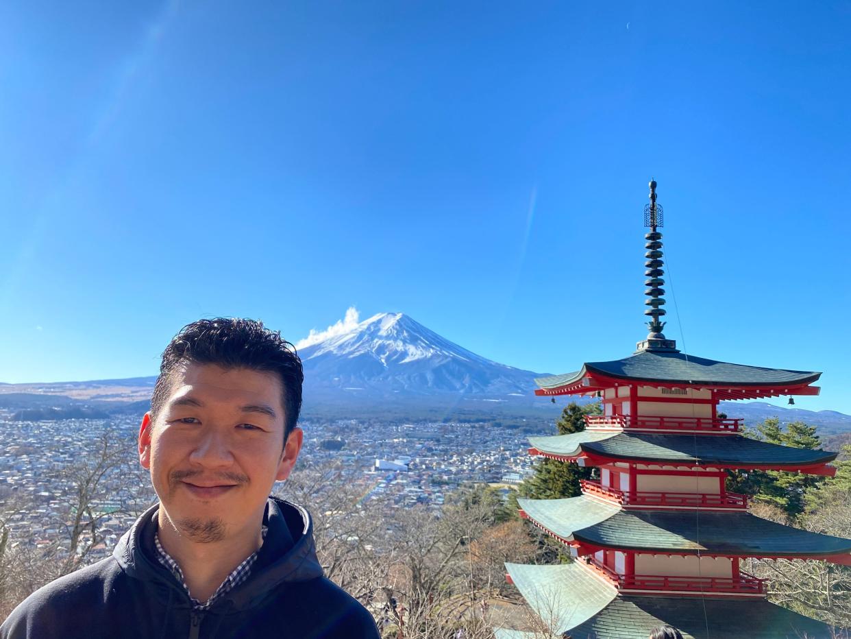 A man poses with Mount Fuji in the background.