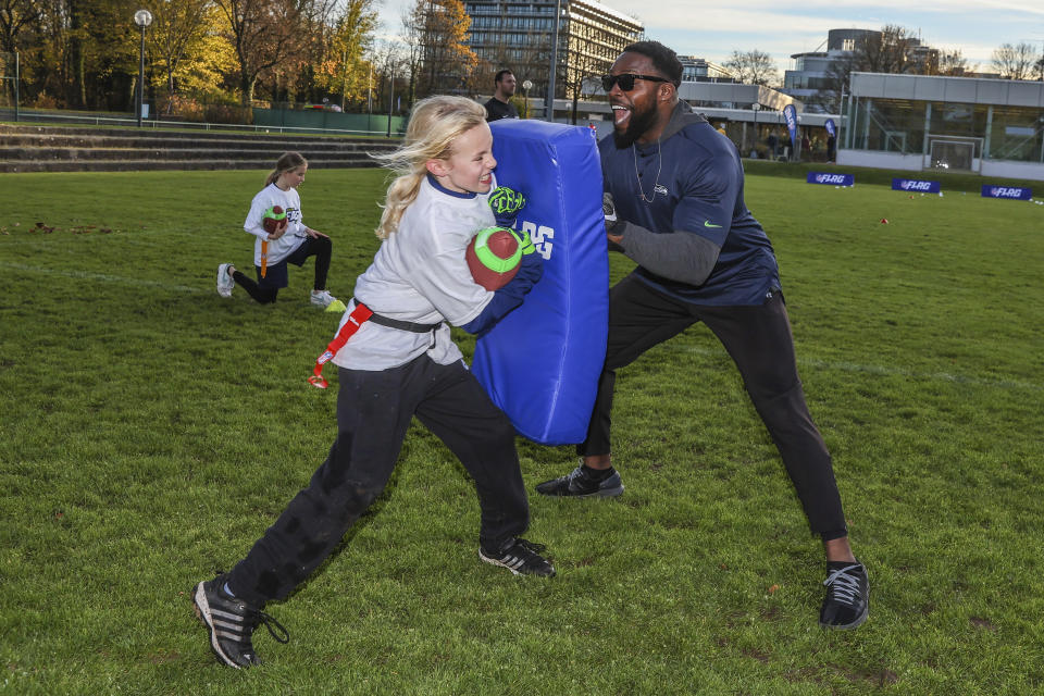 FILE - Seattle Seahawks alumnus Robert Turbin coaches youth participating in the NFL FLAG football program on Friday, Nov. 11, 2022, in Munich. This season, 222 women are working in full-time coaching or football operations roles in the NFL, a modest jump from 199 last year but a massive 141% gain since 2020. (AP Photo/Gary McCullough, File)