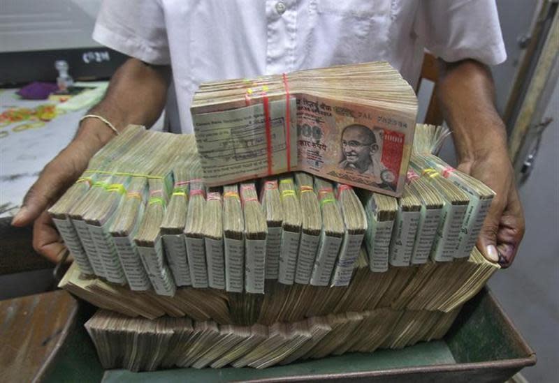 An employee poses with the bundles of rupee notes inside a bank in Agartala, the capital of Tripura August 22, 2013. REUTERS/Jayanta Dey