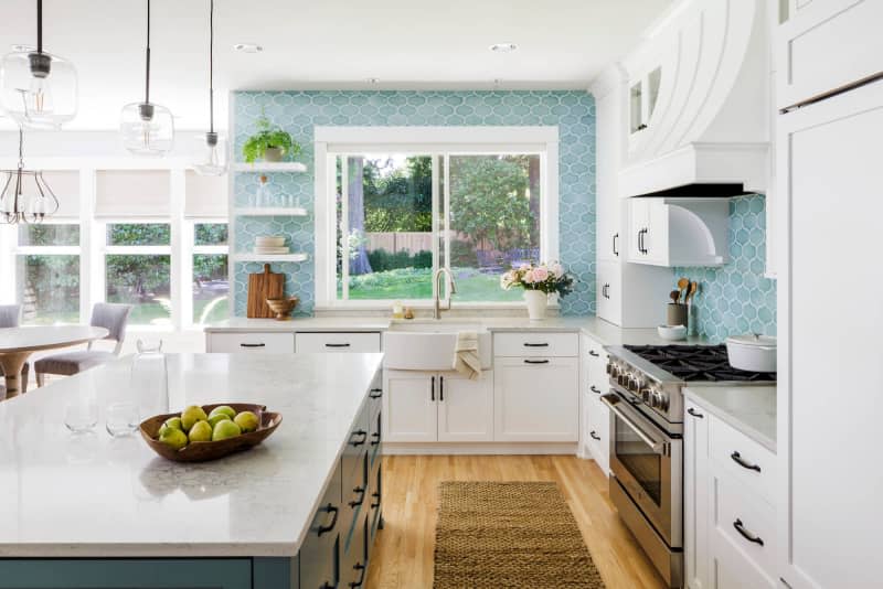 White kitchen with pale blue backsplash, wood floor, and blue island