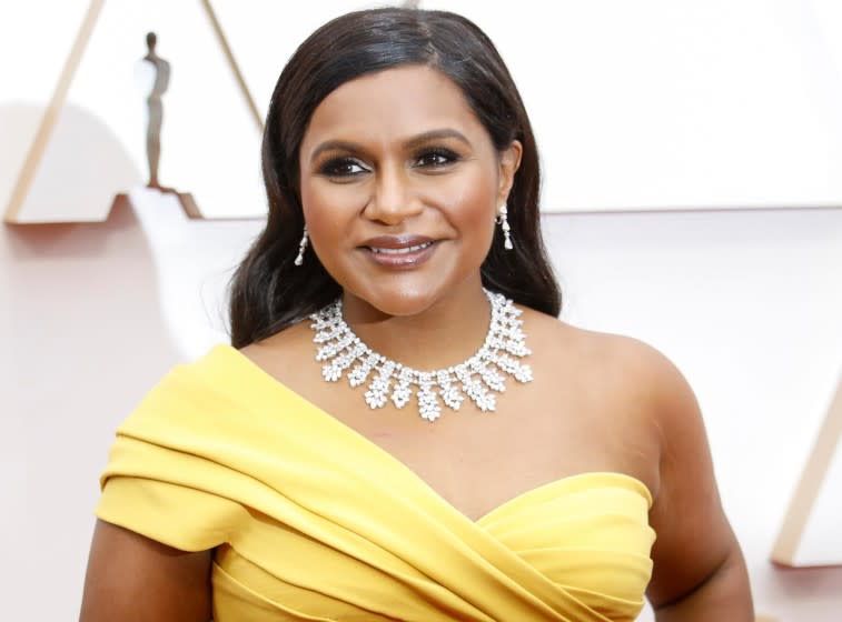 Mindy Kaling posing in a yellow dress