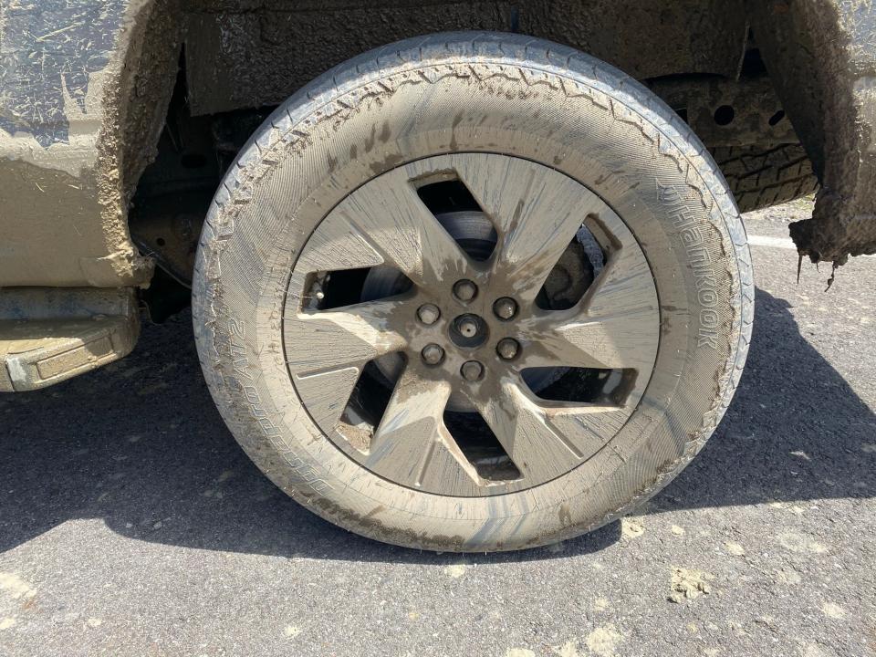 Aerodynamic 22-inch wheel on 2022 Ford F-150 Lightning electric pickup, caked in mud after off roading.