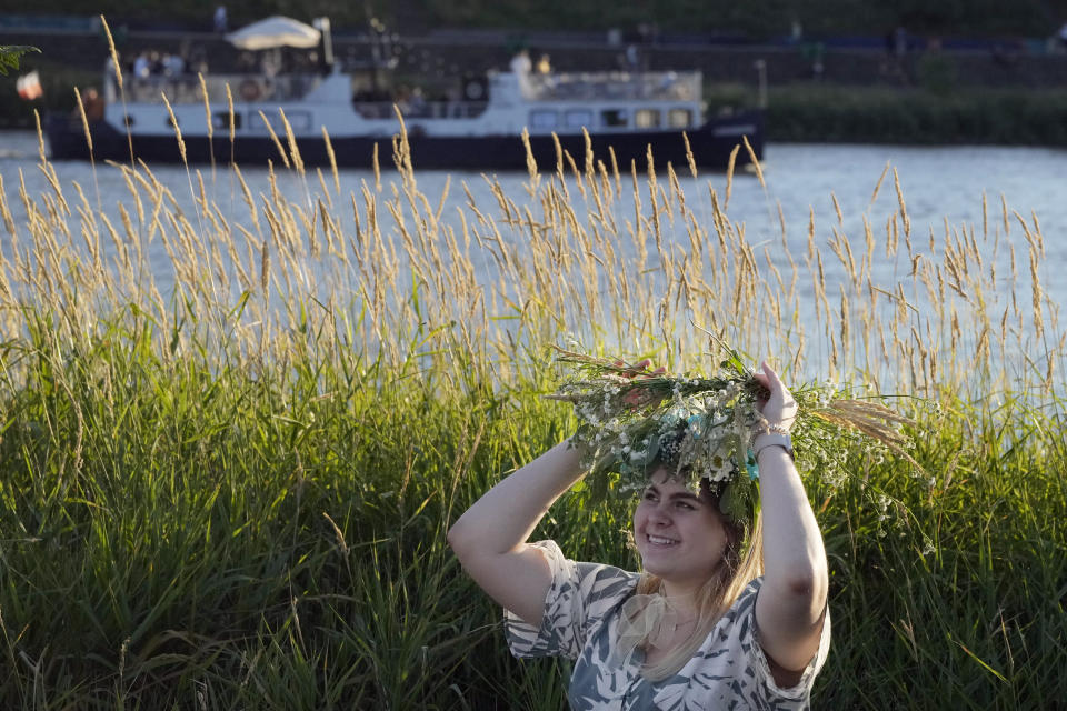 A Ukrainian woman wears an ear of grain braid during a traditional Ukrainian celebration of Kupalo Night, in Warsaw, Poland, on Saturday, June 22, 2024. Ukrainians in Warsaw jumped over a bonfire and floated braids to honor the vital powers of water and fire on the Vistula River bank Saturday night, as they celebrated their solstice tradition of Ivan Kupalo Night away from war-torn home. (AP Photo/Czarek Sokolowski)