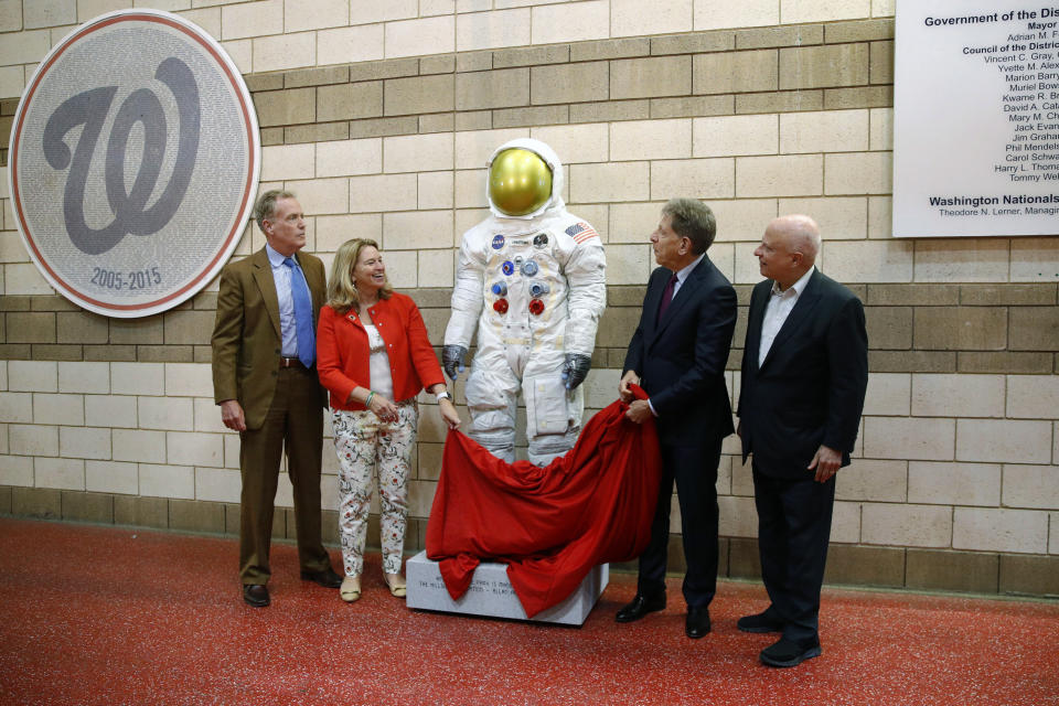FILE - In this June 4, 2019 file photo, Washington Nationals senior vice president Gregory McCarthy, from left, Ellen Stofan of the National Air and Space Museum, statue donor Allan Holt and Nationals owner Mark Lerner unveil a statue of Neil Armstrong's Apollo 11 spacesuit before an interleague baseball game between the Chicago White Sox and the Nationals in Washington. It was unveiled as part of the "Apollo at the Park" program, which will place statues of Armstrong's spacesuit at ballparks across the country to commemorate the moon landing's 50th anniversary. (AP Photo/Patrick Semansky)
