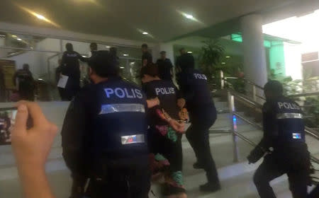 Indonesian Siti Aisyah, who is accused of killing Kim Jong Nam, the estranged half-brother of North Korea's leader, is escorted by police as she arrives at at the Shah Alam High Court on the outskirts of Kuala Lumpur, Malaysia, in this still image taken from a TV footage, October 2, 2017. REUTERS/via Reuters TV