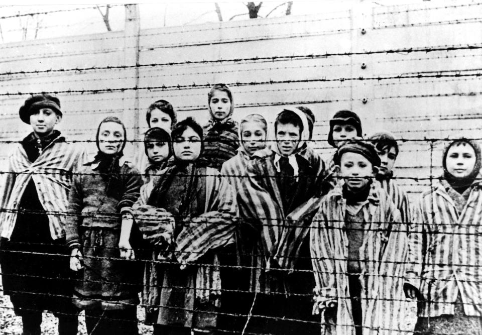 FILE - A picture taken just after the liberation by the Soviet army in January, 1945, shows a group of children wearing concentration camp uniforms at the time behind barbed wire fencing in the Oswiecim (Auschwitz) nazi concentration camp. Germany has agreed to provide more than a half billion euros to aid Holocaust survivors struggling under the burdens of the coronavirus pandemic, the organization that negotiates compensation with the German government said Wednesday. (AP Photo/CAF pap, file)