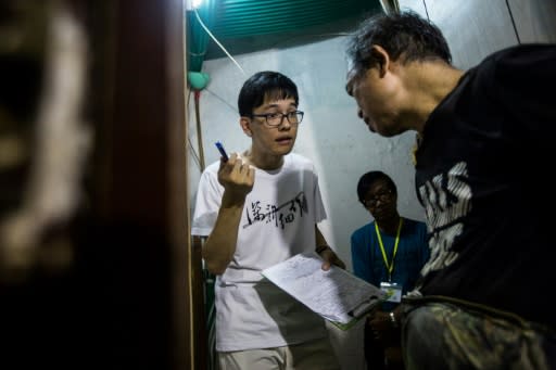 Volunteer Max Leung (left) speaks with a resident of a subdivided flat who requested for his fridge to be repaired