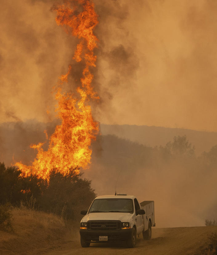 A truck passes by flames during the Ranch Fire in Clearlake Oaks, Calif., on Sunday, Aug. 5, 2018. (AP Photo/Josh Edelson)