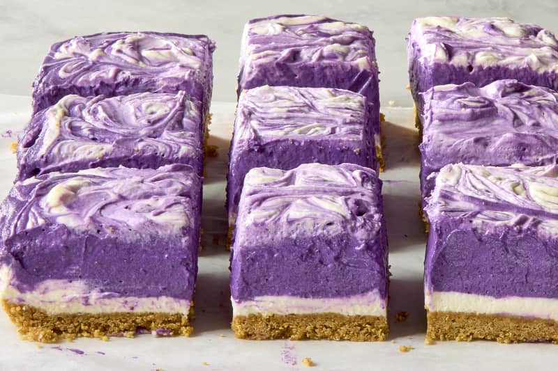 Angled photo of ube dessert bars with layers of purple, white, and cracker crust showing.