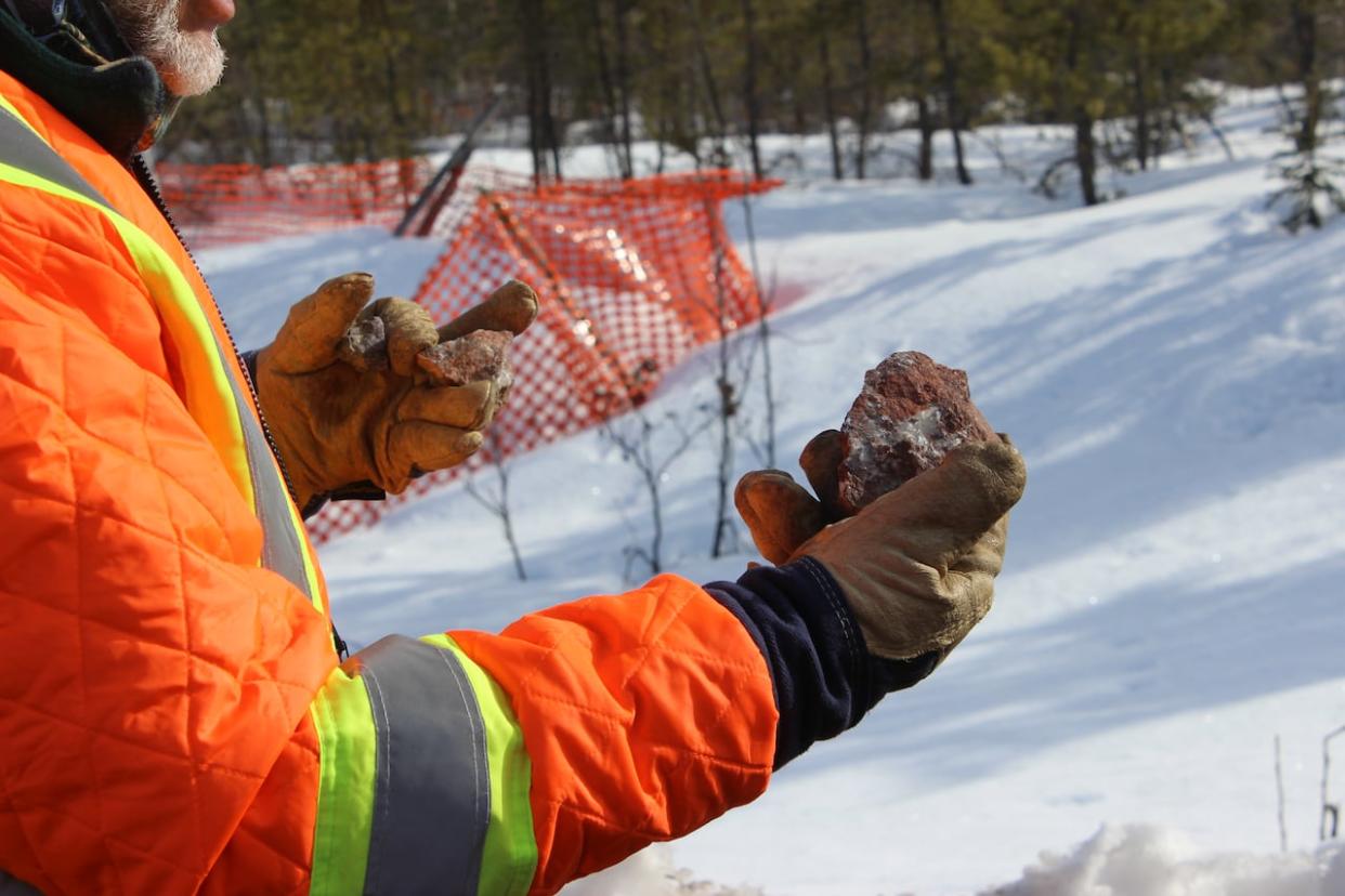 A geologist at the Nechalacho mine project in the N.W.T. holds up a piece of rock in April 2021.  Vital Metals has sold all of its stockpiled rare earth material to Shenghe Resources. (Liny Lamberink/CBC North - image credit)