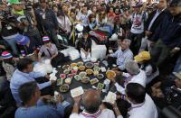 Anti-government protest leader Suthep Thaugsuban (seated, R) eats lunch on the street during a march in central Bangkok January 21, 2014. REUTERS/Paul Barker