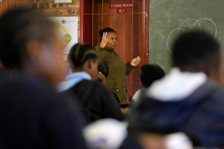 Lebohang Mphuthi assist students during a class at the Omar H.S. Ebrahim Primary School in Lotus Gardens, west of Pretoria, South Africa, Tuesday, July 25, 2023. (AP Photo/Themba Hadebe)