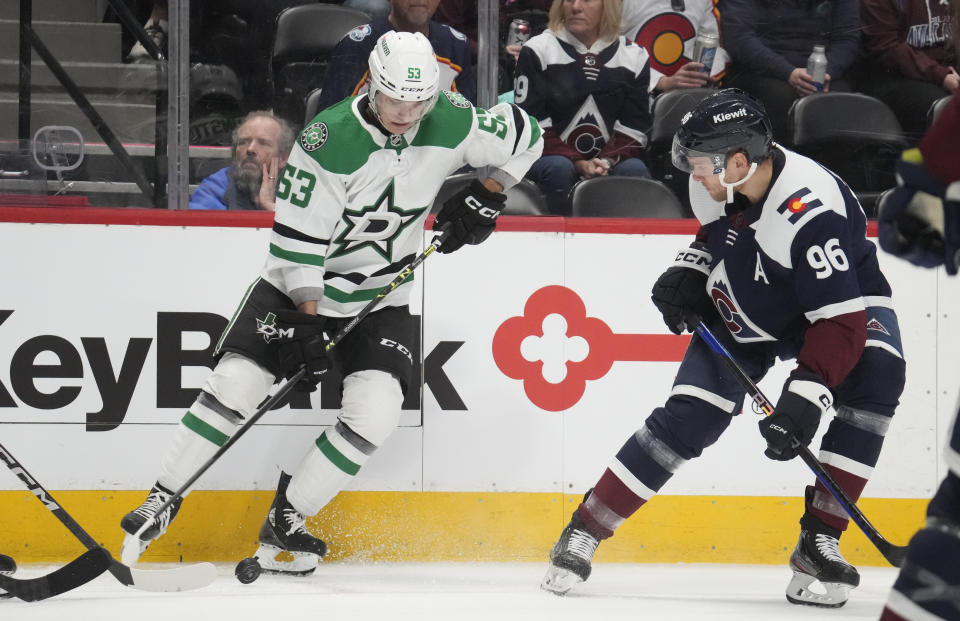 Dallas Stars center Wyatt Johnston, left, collects the puck as Colorado Avalanche right wing Mikko Rantanen defends in the second period of an NHL hockey game Saturday, April 1, 2023, in Denver. (AP Photo/David Zalubowski)