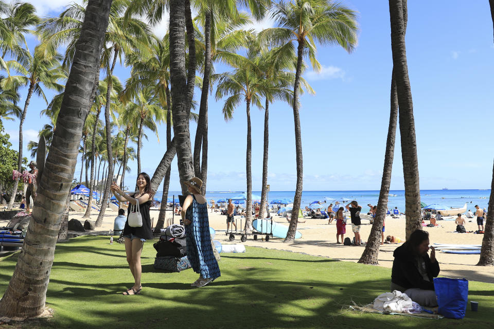 Two people take pictures on Waikiki Beach, Thursday, June, 23, 2022 in Honolulu. In a major expansion of gun rights after a series of mass shootings, the Supreme Court said Thursday that Americans have a right to carry firearms in public for self-defense.