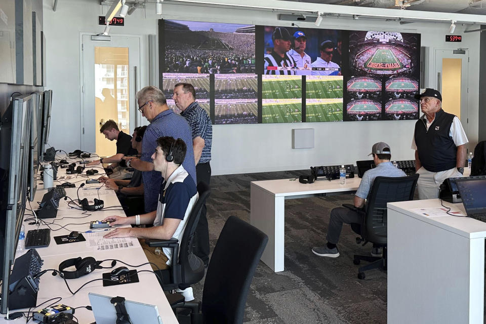 Alberto Riveron, third from left wearing eyeglasses, the Atlantic Coast Conference supervisor of football officials, works in the league’s new gameday operations, Saturday, Sept. 2, 2023, in Charlotte, N.C. Seven years ago, the ACC and SEC used collaborative replay on an experimental basis and reported their findings to the NCAA rules committee, while the Pac-12 used it on a limited basis in that 2016 season. Now it's an integral part of officiating across the sport's highest level every week. (AP Photo/Aaron Beard)