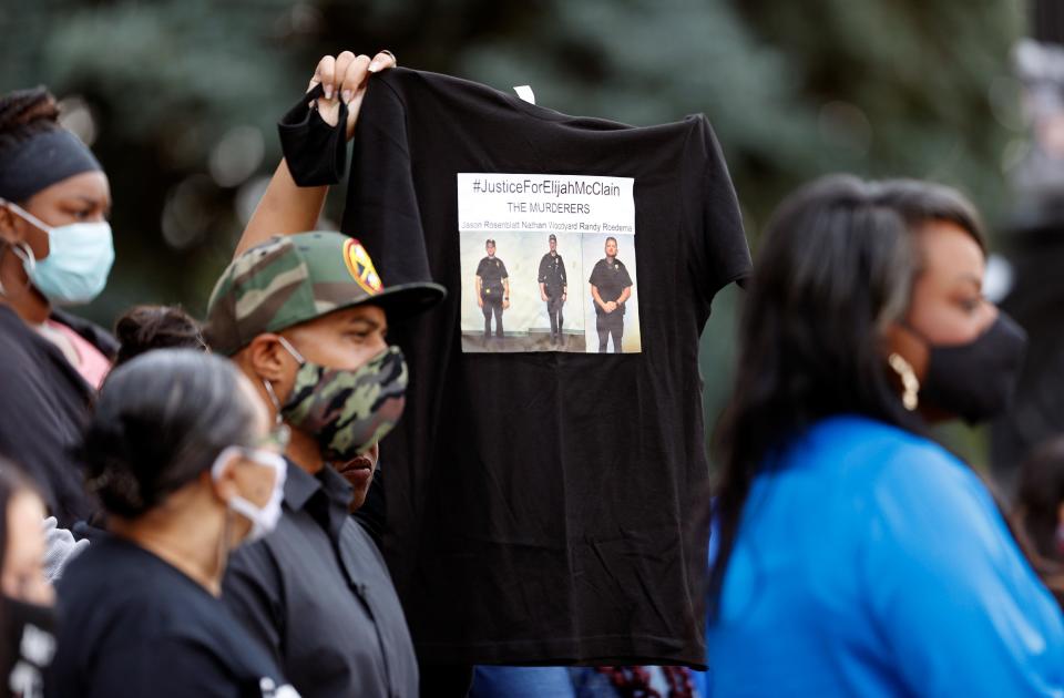 A supporter holds up a shirt to call attention to the death of Elijah McClain in August 2019 in Aurora, Colo., during a news conference on the west steps of the State Capitol after Colorado Governor Jared Polis signed a broad police accountability bill Friday, June 19, 2020, in downtown Denver.
