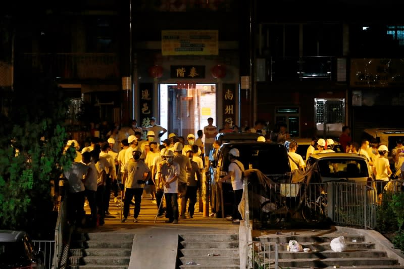 FILE PHOTO: Men in white T-shirts and holding poles are seen in Yuen Long after attacking anti-extradition bill demonstrators at a train station in Hong Kong