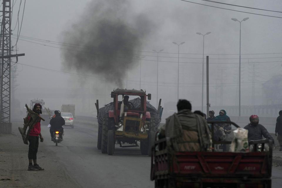 A tractor releases smoke as it moves along a road as smog envelops the area, in Lahore, Pakistan, Monday, Jan. 15, 2024. Lahore is in an airshed, an area where pollutants from industry, transportation and other human activities get trapped and cannot disperse easily. (AP Photo/K.M. Chaudary)