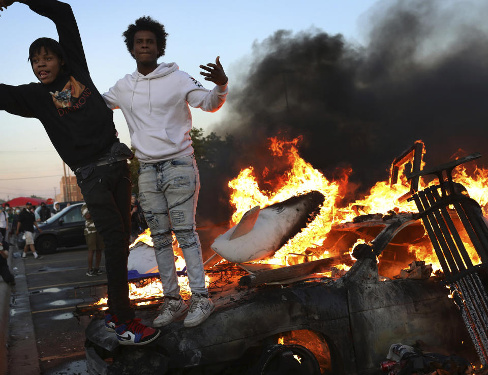 Young men stand atop a burning car in the Target parking lot E. Lake St. during a third night of unrest following the death of George Floyd while in Minneapolis police custody early in the week and seen Thursday, May 28, 2020, in Minneapolis, MN.] DAVID JOLES • david.joles@startribune.com Folo on death of George Floyd at hands of Minneapolis police.**Edward Washington,cq/Star Tribune via AP)