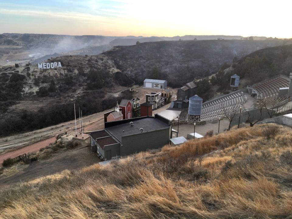 A wildfire smolders near the Burning Hills Amphitheatre Thursday, April 1, 2021 near Medora, N.D. Officials say firefighters have stopped a wildfire from spreading in the western North Dakota tourist town of Medora, where its 100 residents were forced to evacuate. (Tom Stromme/The Bismarck Tribune via AP)