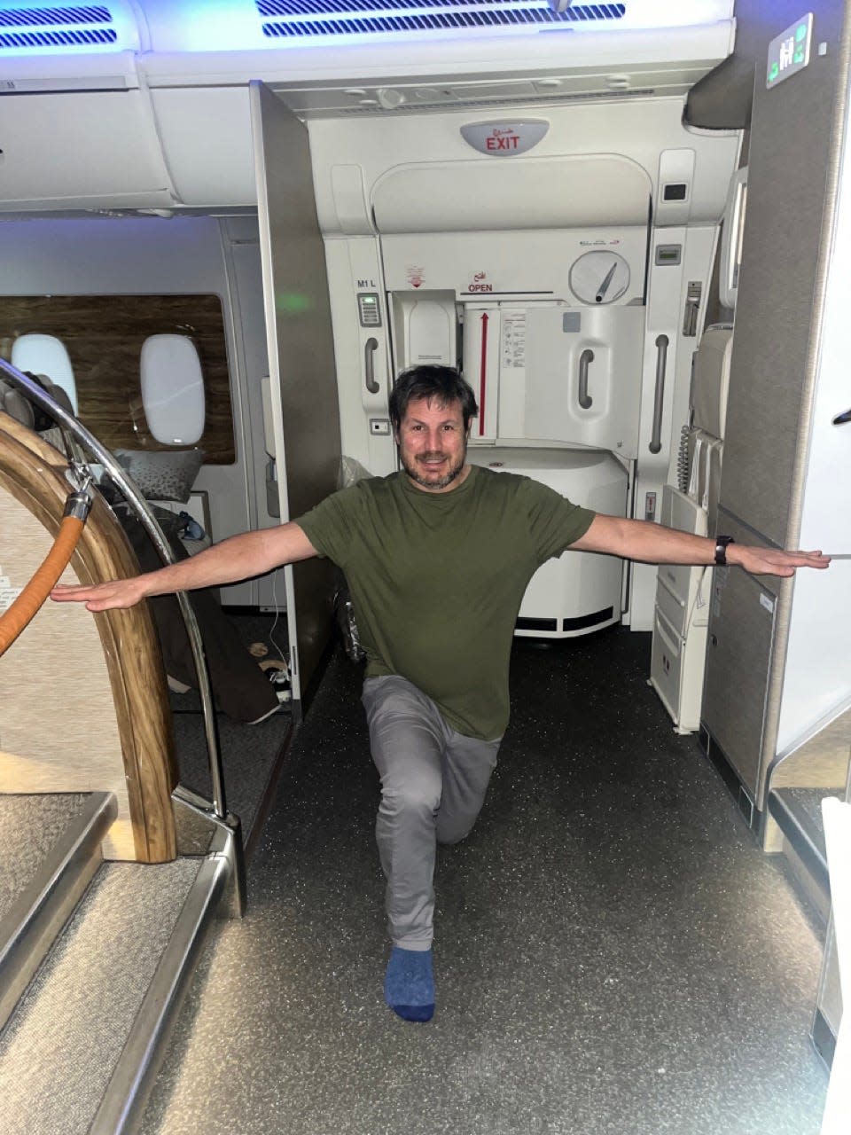 Author Ash Jurberg sitting on plane seat in premium economy  stretching on plane 